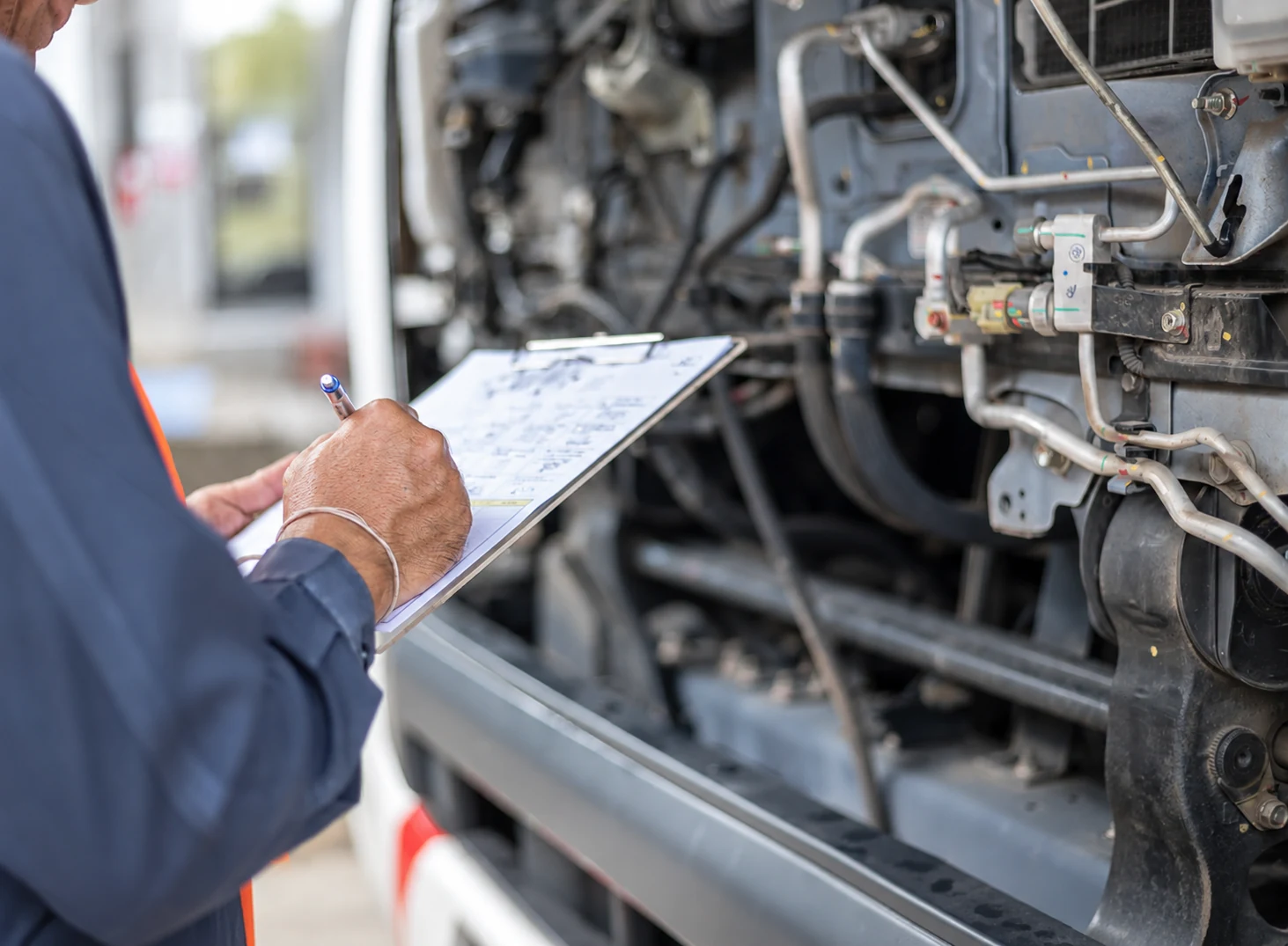 Technician documenting an inspection beside an exposed truck engine