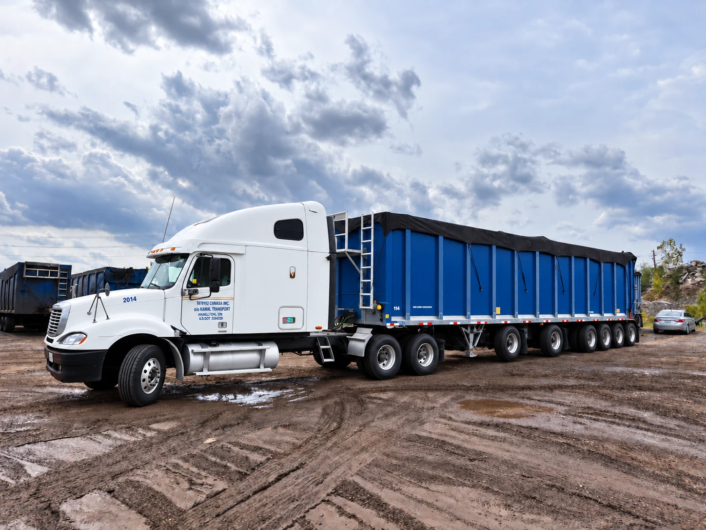 Kamal Transport white tractor with a blue open-top trailer