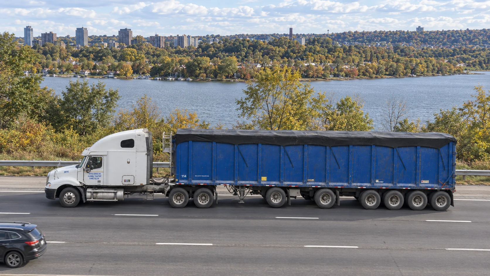 Kamal Transport white tractor and blue trailer beside the water